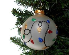 a glass ornament hanging from a christmas tree with lights and decorations on it