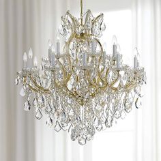 a chandelier hanging from the ceiling in a room with white walls and curtains