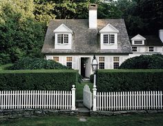 a white house surrounded by hedges and trees