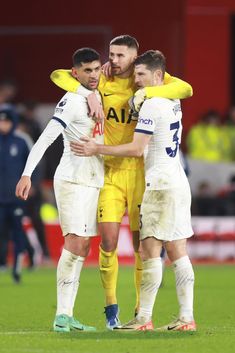 three soccer players congratulate each other on the field