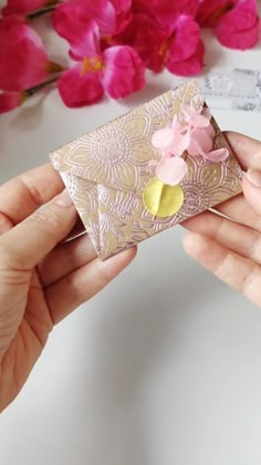 a person holding an envelope with pink flowers on it and a flower pin in the middle