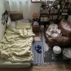 a small bedroom with a bed, chair and bookshelf in the corner next to a window