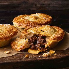 three meat pies sitting on top of a wooden table