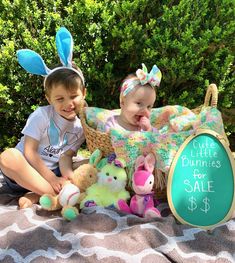 two young children sitting on a blanket with stuffed animals in front of them and a sign that says little dummies for sale