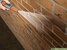 a person spraying water on a brick wall with a sprayer in their left hand