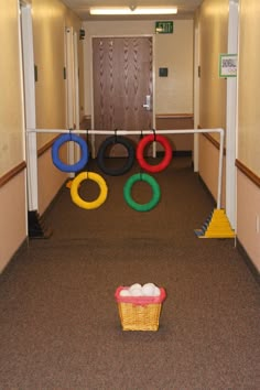 an empty hallway with several colorful rings on the floor and a basket full of eggs