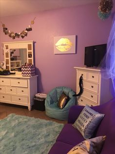 a living room filled with furniture and a tv on top of a dresser next to a purple wall