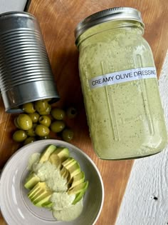 an avocado and some olives are next to a jar of creamy olive dressing