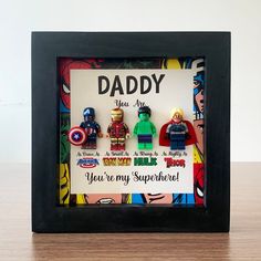 a photo frame with the words daddy and superheros in it on a wooden table