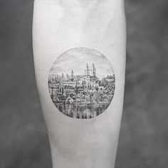 a black and white photo of a cityscape in a circle tattoo on the leg