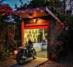 a motorcycle is parked in front of a small shed with lights on the roof and windows