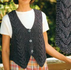 a woman wearing a gray knitted vest and plaid skirt holding an object in her hands