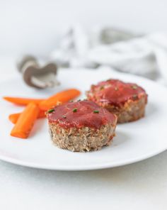 two meatloaf muffins on a white plate with carrots and ketchup