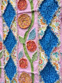 a close up of a colorful quilt with flowers on it