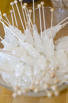 a glass bowl filled with lots of white pins and needles on top of a wooden table