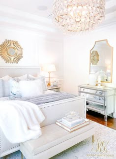 a white bedroom with a chandelier above the bed