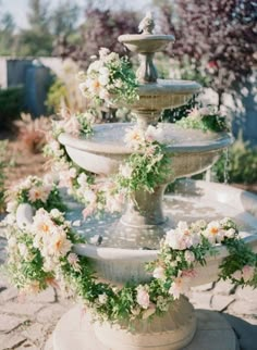 a water fountain decorated with flowers and greenery