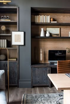 a living room filled with furniture and bookshelves next to a wooden desk topped with a computer