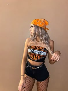 a woman in fishnet stockings and an orange bandana is posing for the camera