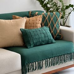 a couch with many pillows on it and a potted plant in the back ground