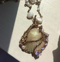 the necklace is adorned with pearls and other jewelry items, including a shell on a chain