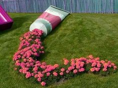 a pink tube laying on top of a lush green field next to flowers and a slide