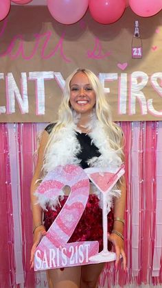 a woman standing in front of a pink and white backdrop holding a sign that says twenty