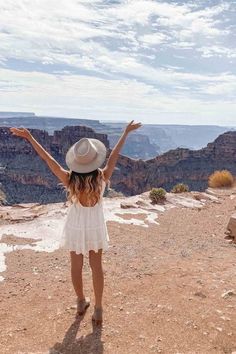 a woman standing on top of a mountain with her arms outstretched