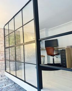 an office area with glass walls, desks and chair in front of brick wall