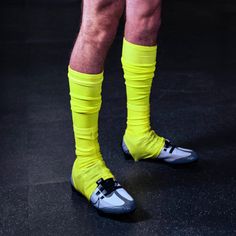 the legs and feet of a man wearing yellow socks with black straps, standing in a dark room