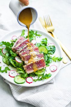 someone is pouring sauce on a plate of food