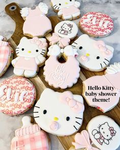 hello kitty baby shower cookies are arranged on a cutting board with pink and white icing