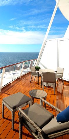 chairs and tables are on the deck of a cruise ship, overlooking the ocean with bright blue skies