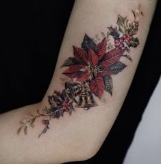 a woman with a tattoo on her arm has a bell and poinsettis