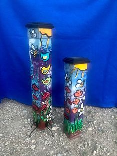 two colorful vases sitting next to each other on top of a stone ground with blue background