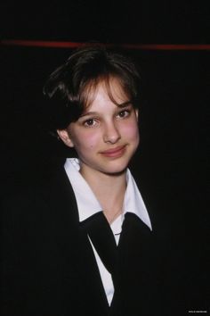 a young woman in a black and white suit posing for the camera with dark background