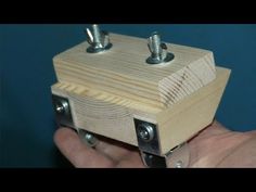 a hand holding a wooden box with two screws on it