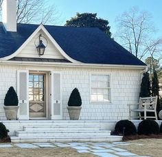 a white house with two chairs on the front porch and an entry way leading to it