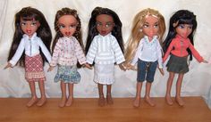 five dolls are lined up next to each other on a wooden shelf with white curtains behind them