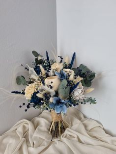 a bouquet of flowers sitting on top of a white cloth covered bed next to a wall