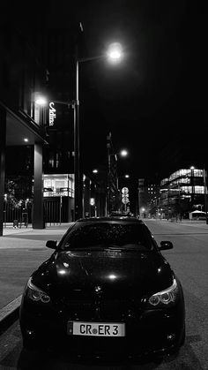 a car is parked on the side of the road at night time with street lights in the background