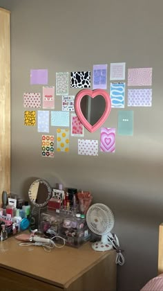 a desk with many crafting supplies on it and a heart hanging from the wall