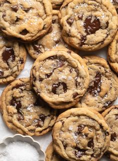 chocolate chip cookies are piled on top of each other with powdered sugar around them