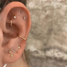 a woman wearing three different types of ear piercings