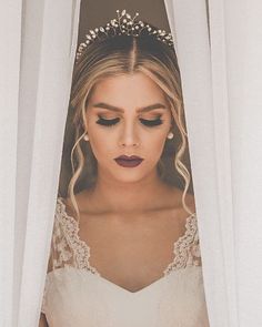 a woman wearing a tiara standing in front of white curtains with her eyes closed