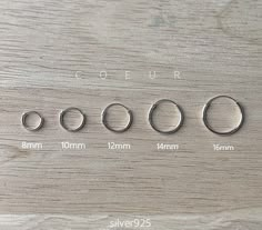 four different sizes of rings are shown on a wooden surface with measurements for each ring