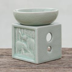 a white ceramic bowl sitting on top of a small square object with holes in it