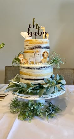 a three tiered cake sitting on top of a table next to green plants and greenery