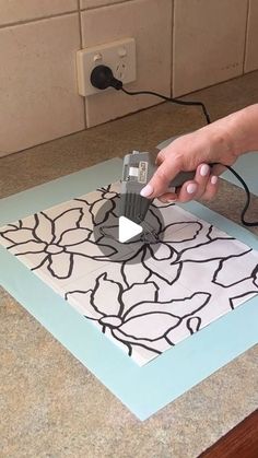 a person using a power tool to cut out a piece of paper on the counter