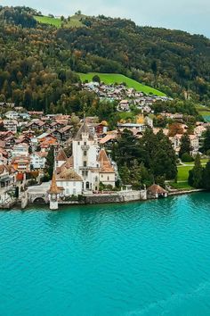 an aerial view of a small town on the edge of a body of blue water